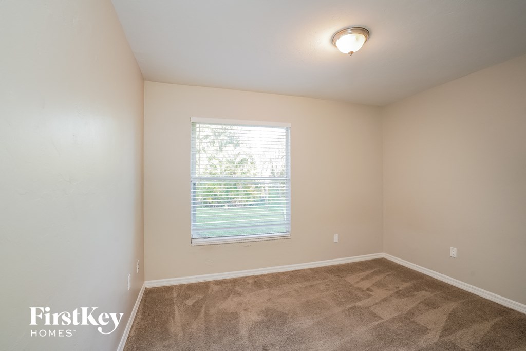 A room with a carpeted floor and a window with blinds.