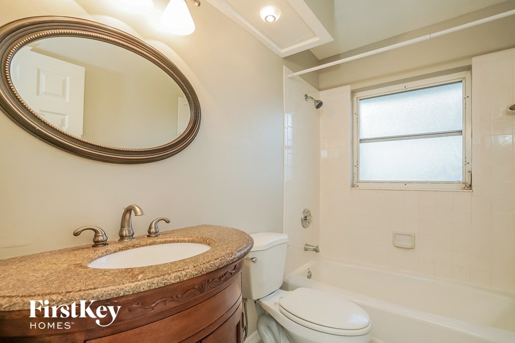 A bathroom with a marble countertop and a round mirror.