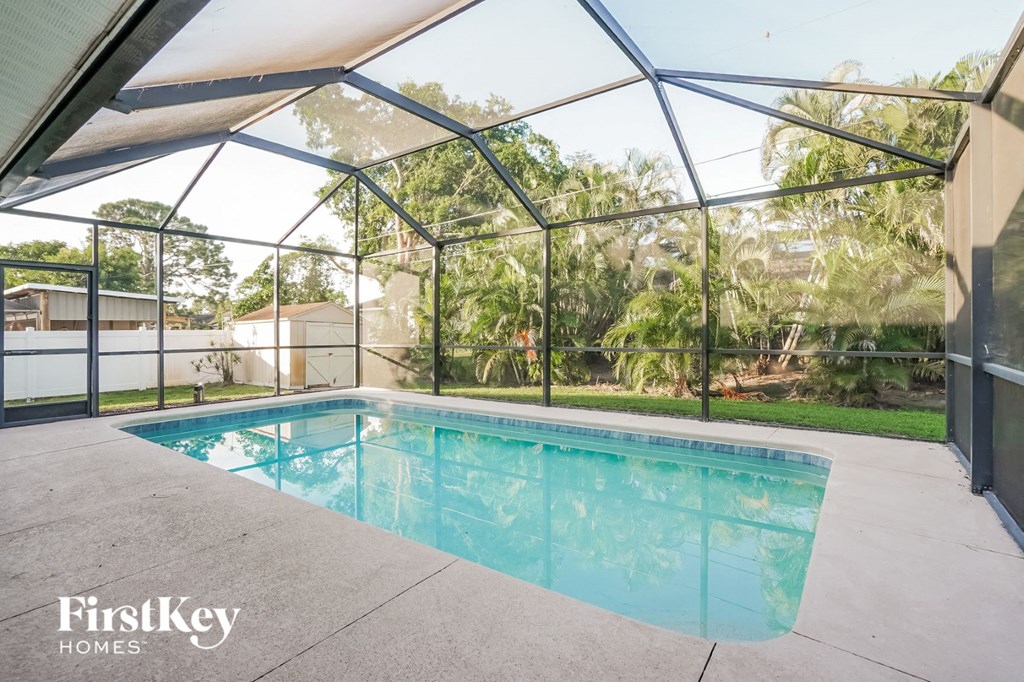 A swimming pool under a glass enclosure with trees in the background.