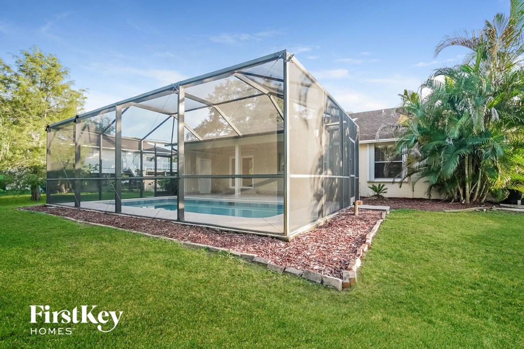 A modern house with a glass wall and a pool in the backyard.