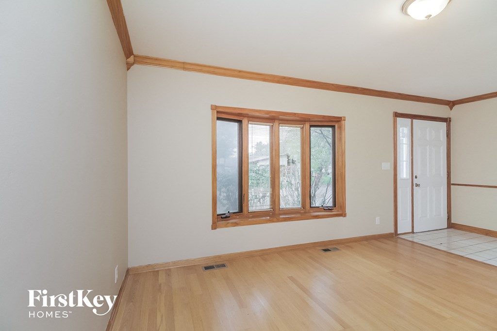 the living room of an empty house with wooden floors and a window