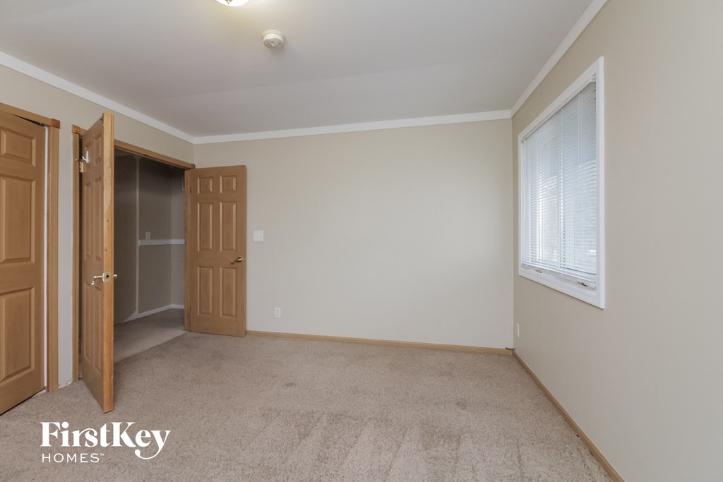 a bedroom with a door to a closet and a window