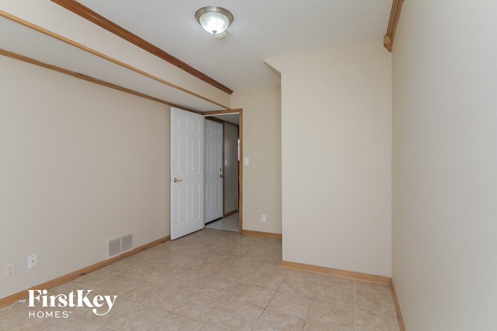 a bedroom with a door to a hallway and a tile floor