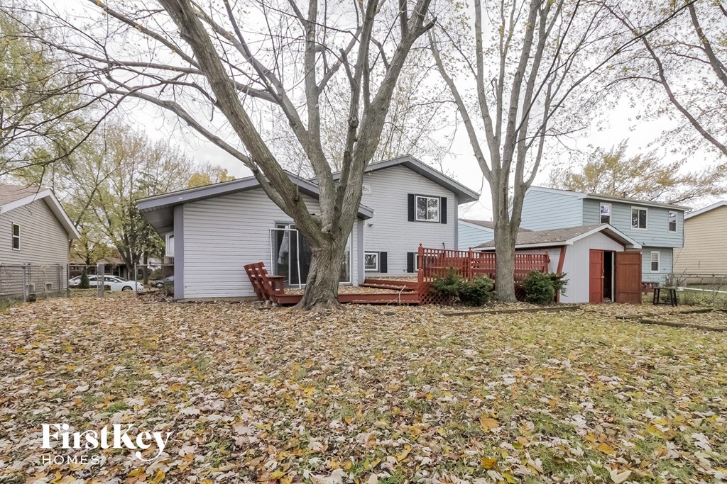 a white house with a yard with trees and a red deck