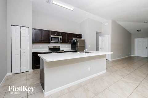 A kitchen with a white island and dark brown cabinets.