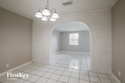 a dining room with a brick archway and white tiled floor