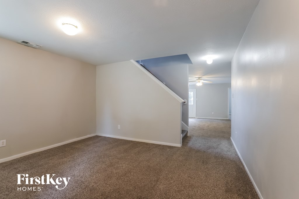 a room with a carpeted floor and white walls and a staircase