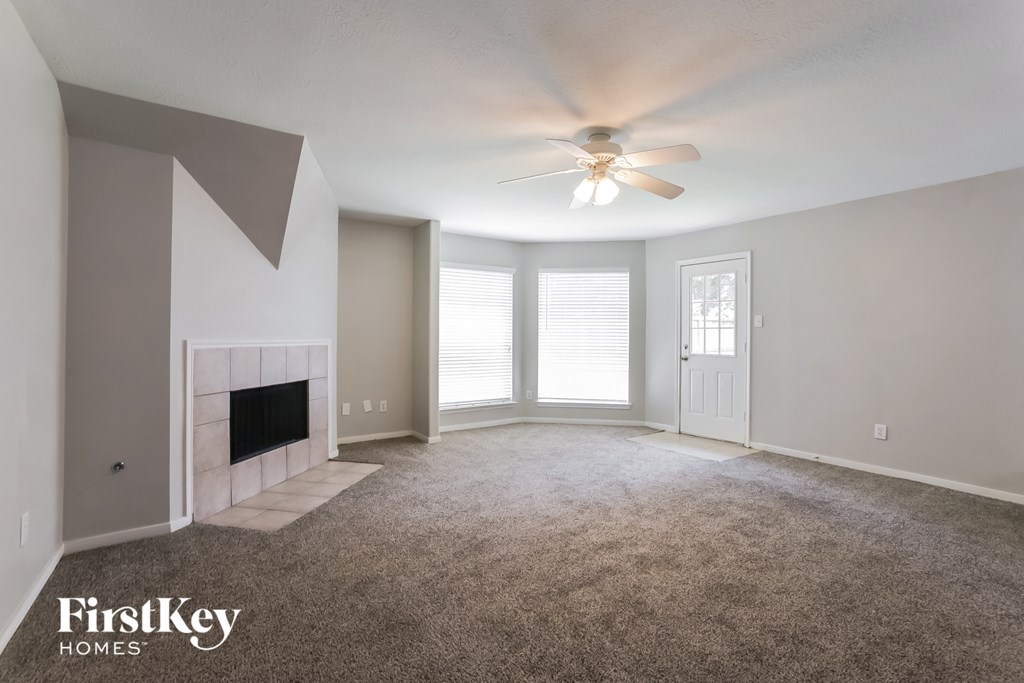 an empty living room with a ceiling fan and a fireplace