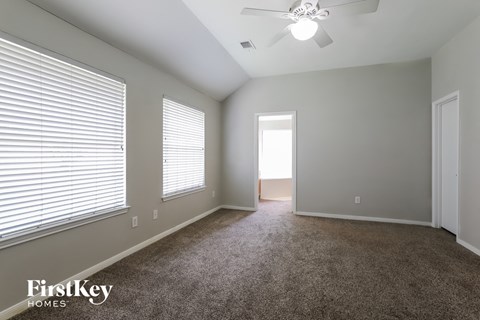 a spacious living room with carpet and a ceiling fan