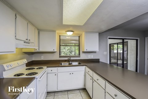 A kitchen with white cabinets and a stove top oven.