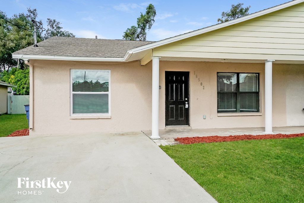 a beige house with a driveway and a black door