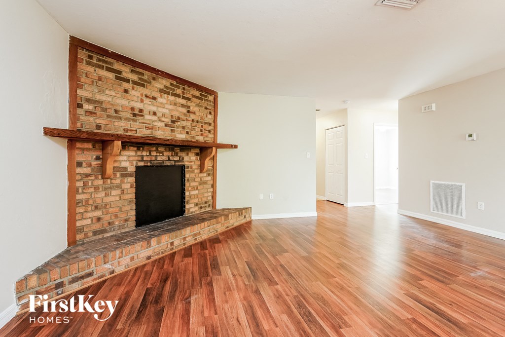 a living room with a brick fireplace and wooden floors