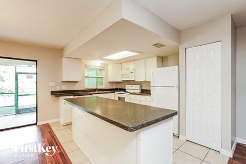a kitchen with an island with granite counter top and white appliances