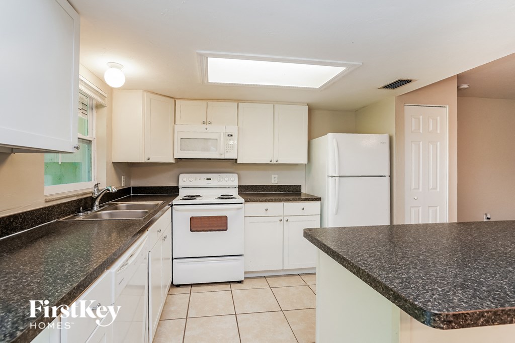 a kitchen with white appliances and granite counter tops