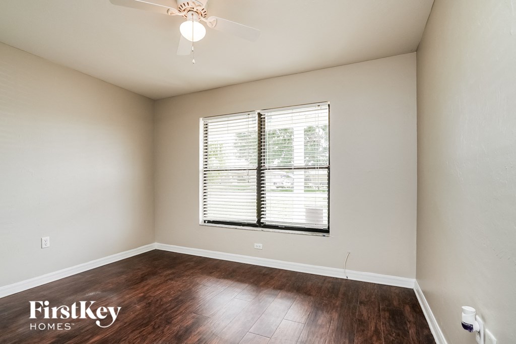 the spacious living room with wood flooring and a large window