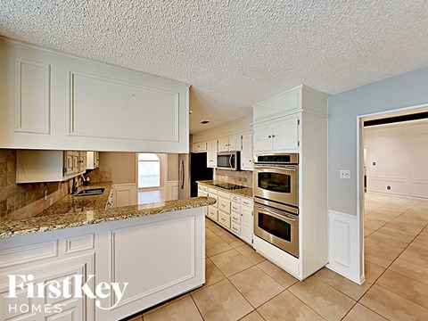 A kitchen with white cabinets and a tile floor.