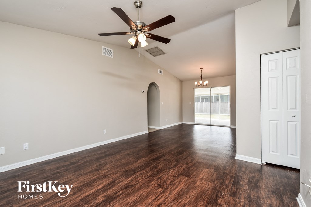 A spacious room with a ceiling fan and wooden flooring.