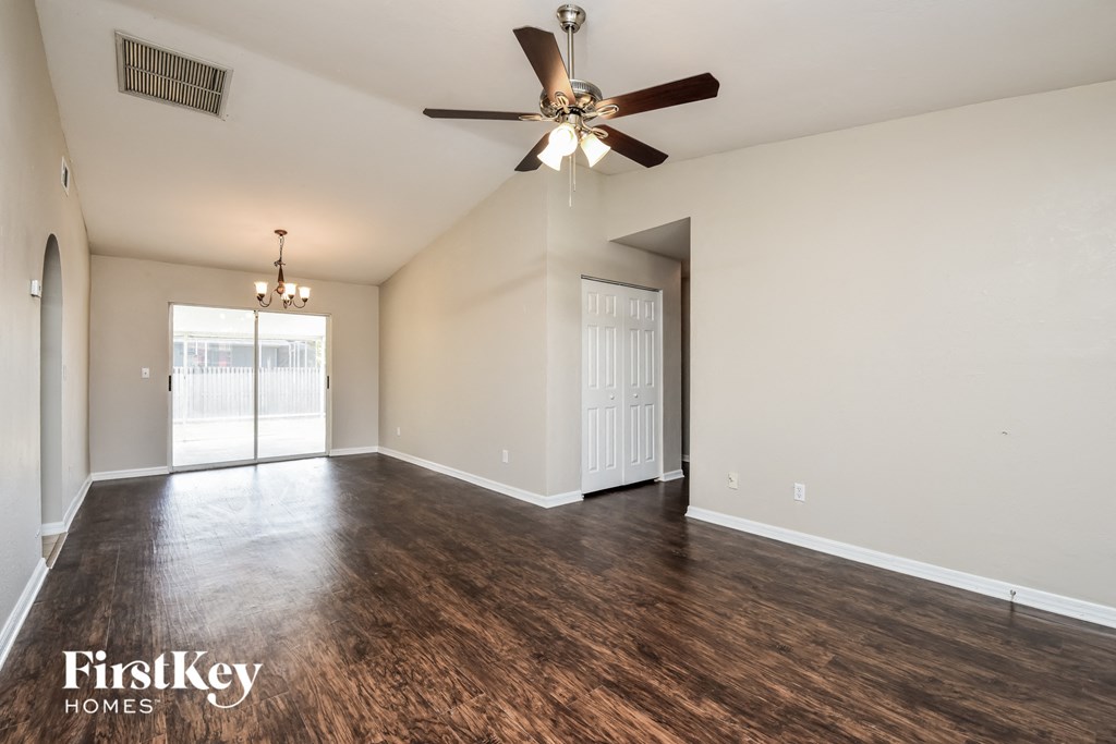 A spacious room with a ceiling fan and wooden flooring.