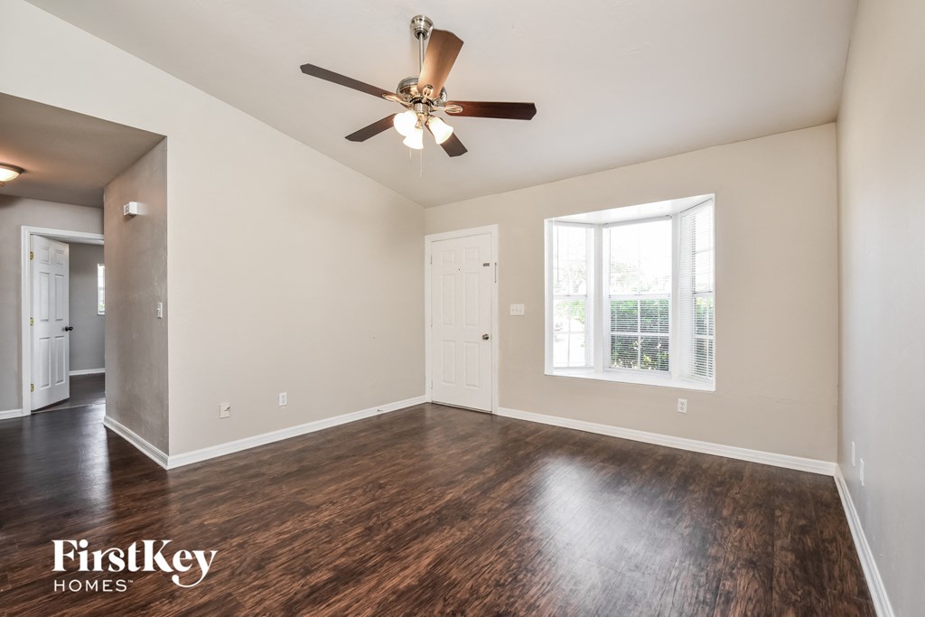 A spacious room with a ceiling fan and hardwood floors.