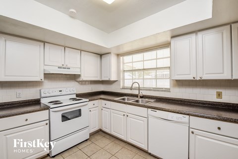 A kitchen with white cabinets and a white stove top oven.