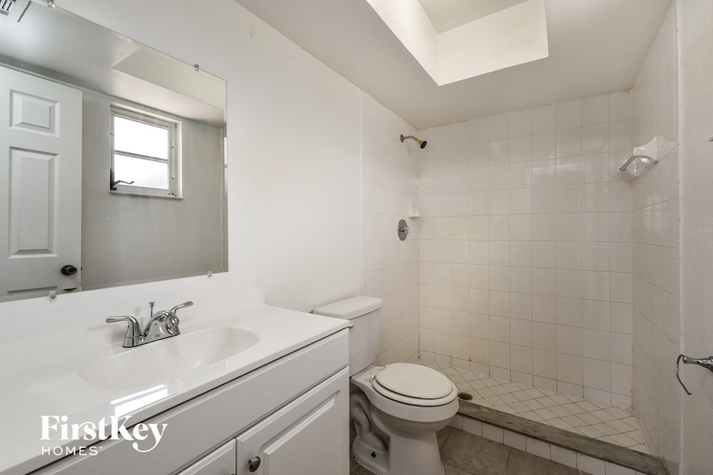 A white bathroom with a toilet, sink, and mirror.