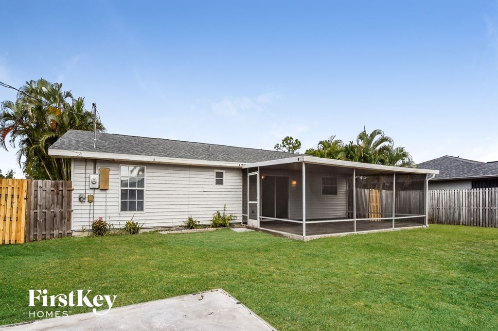 A house with a fence and a tree in the backyard.