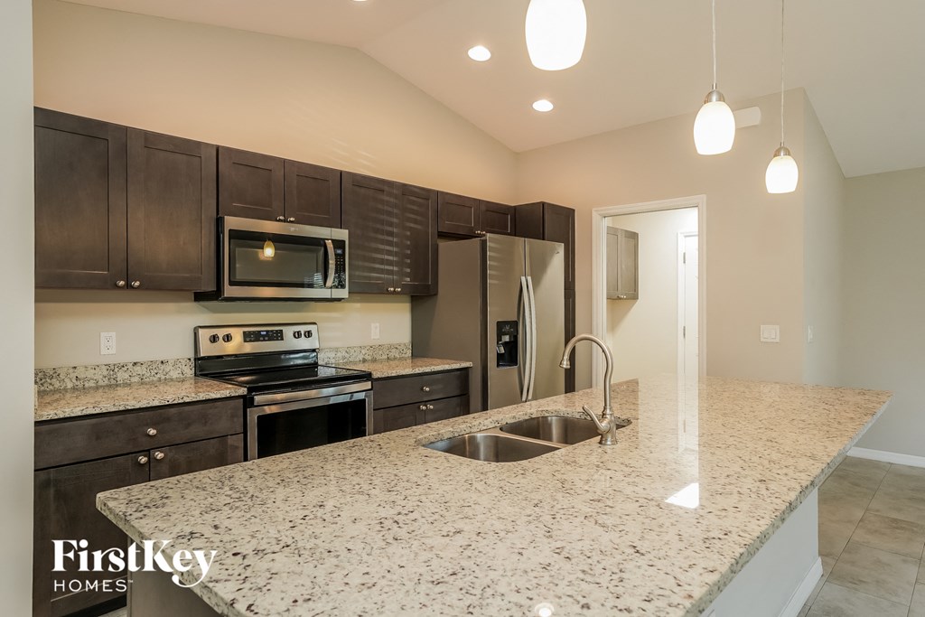 A kitchen with granite countertops and dark wood cabinets.