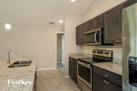 A kitchen with a sink, microwave, oven and cabinets.