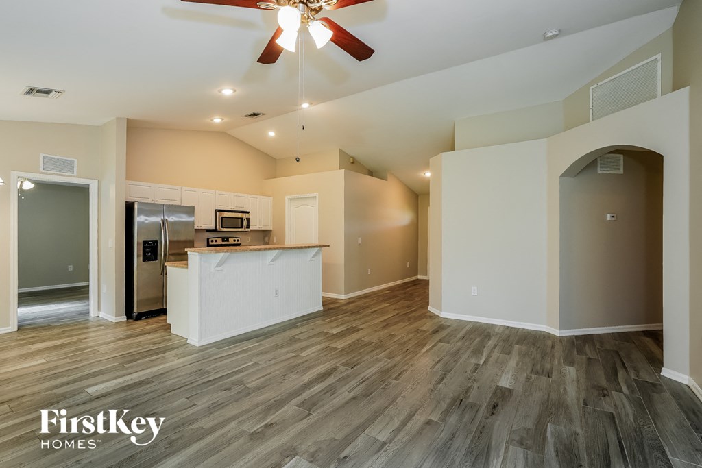 a living room with a kitchen and a ceiling fan