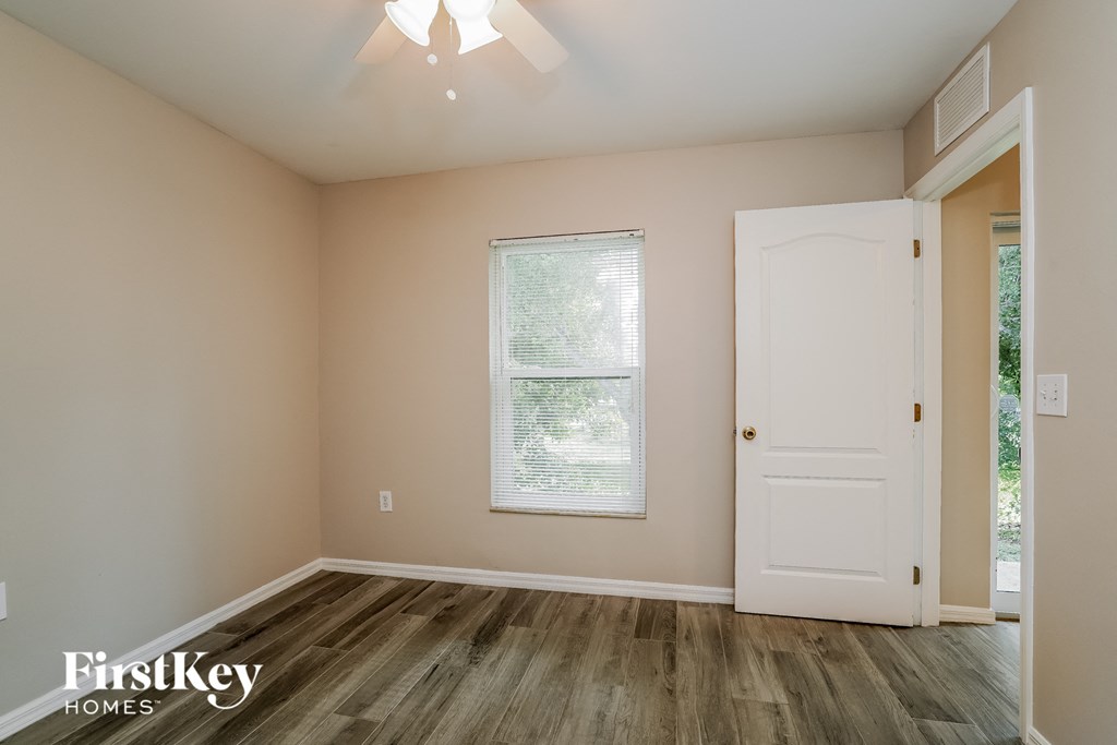 the living room of a home with a white door and wood floors
