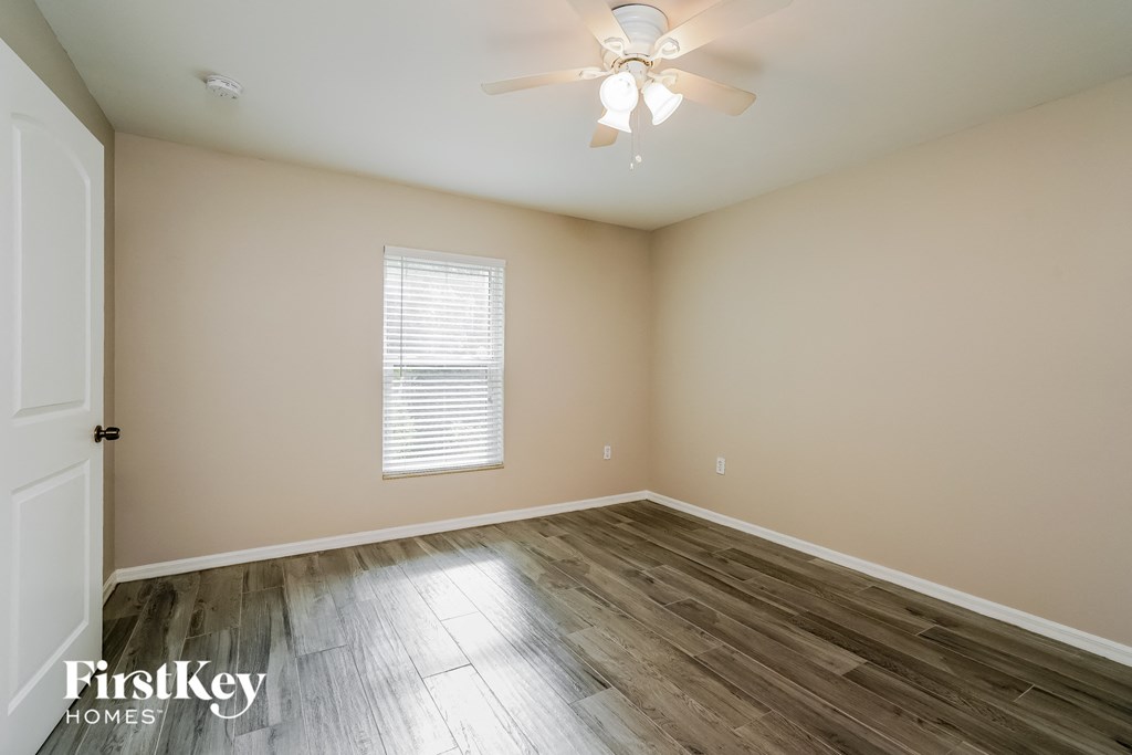 a bedroom with hardwood flooring and a ceiling fan