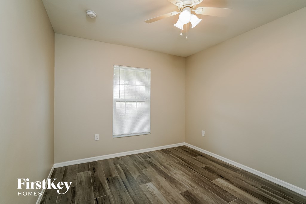 a bedroom with wood flooring and a ceiling fan