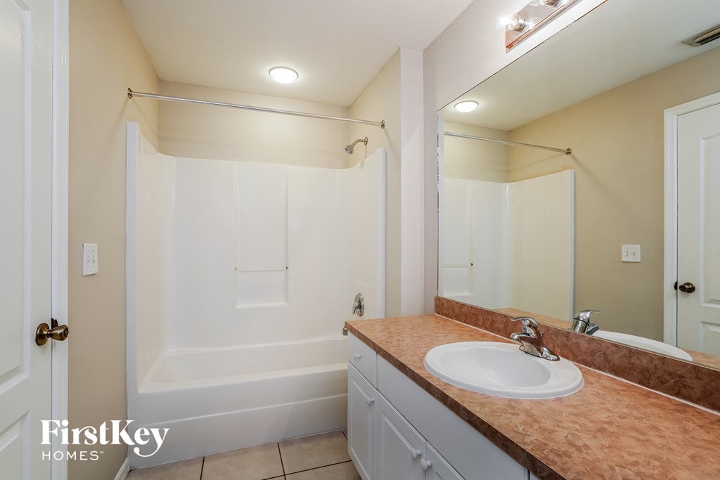 a bathroom with a sink and a shower and a mirror