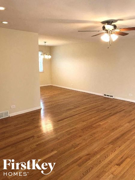 an empty living room with a ceiling fan and wood floors