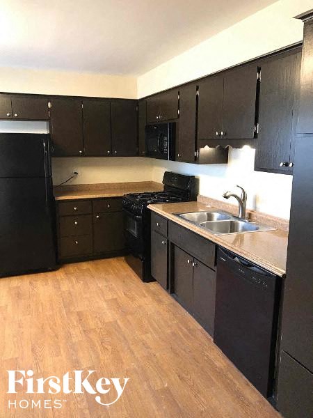 an empty kitchen with black cabinets and a sink