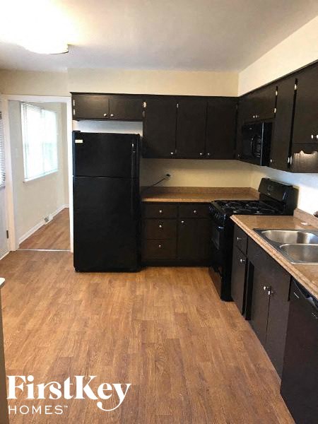 a kitchen with black appliances and a wooden floor