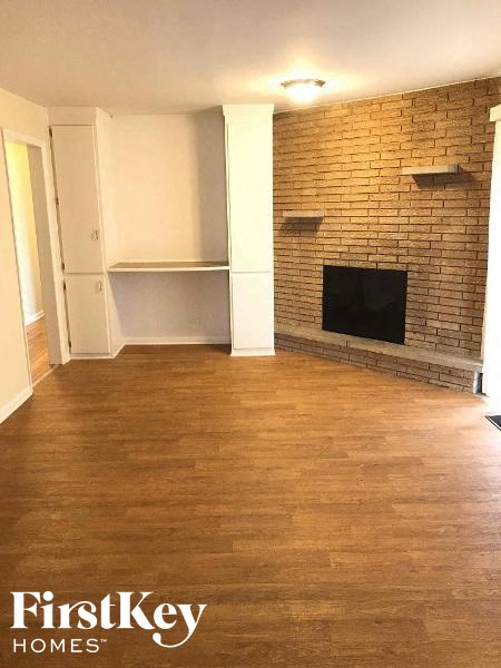 an empty living room with a brick wall and a fireplace