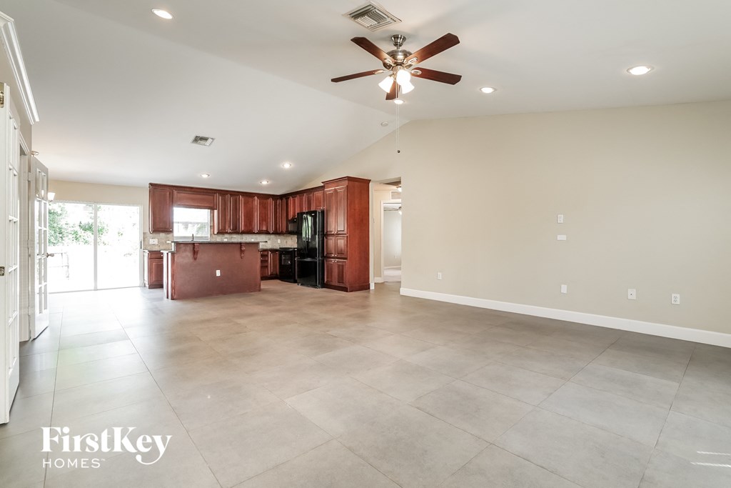 A spacious living room with a kitchen in the background.