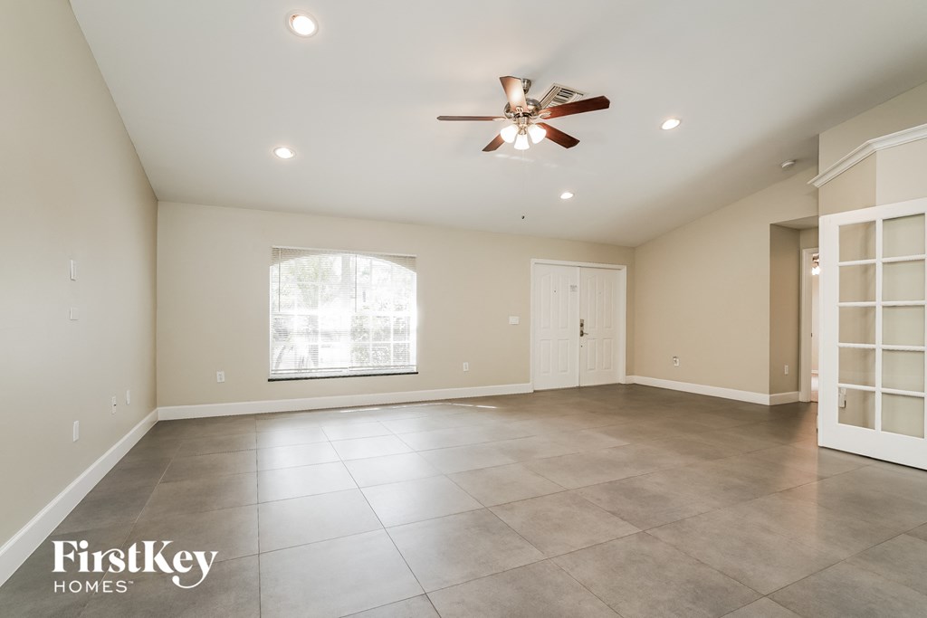 A spacious room with a ceiling fan and a large window.
