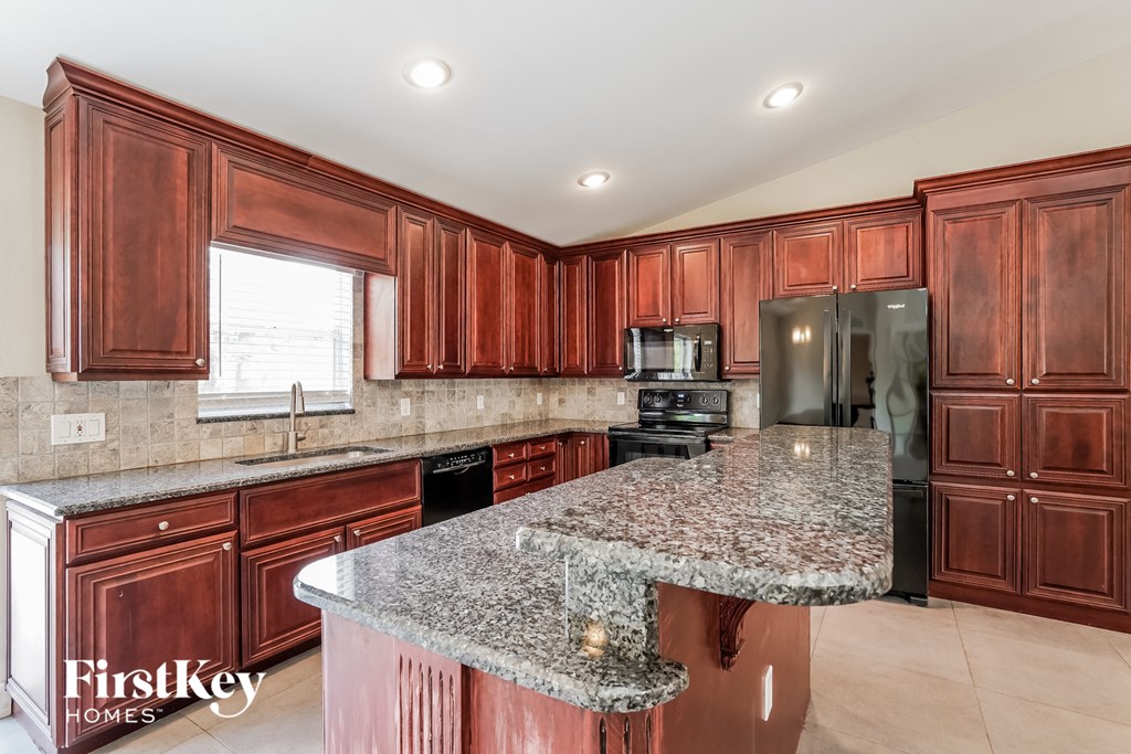 A kitchen with brown cabinets and granite countertops.