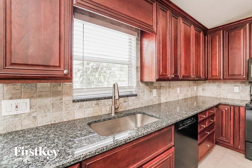 A kitchen with red cabinets and a granite countertop.