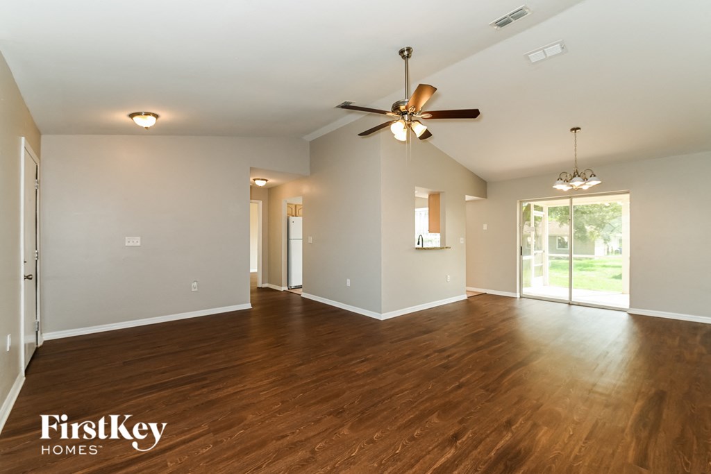 an empty living room with wood floors and a ceiling fan