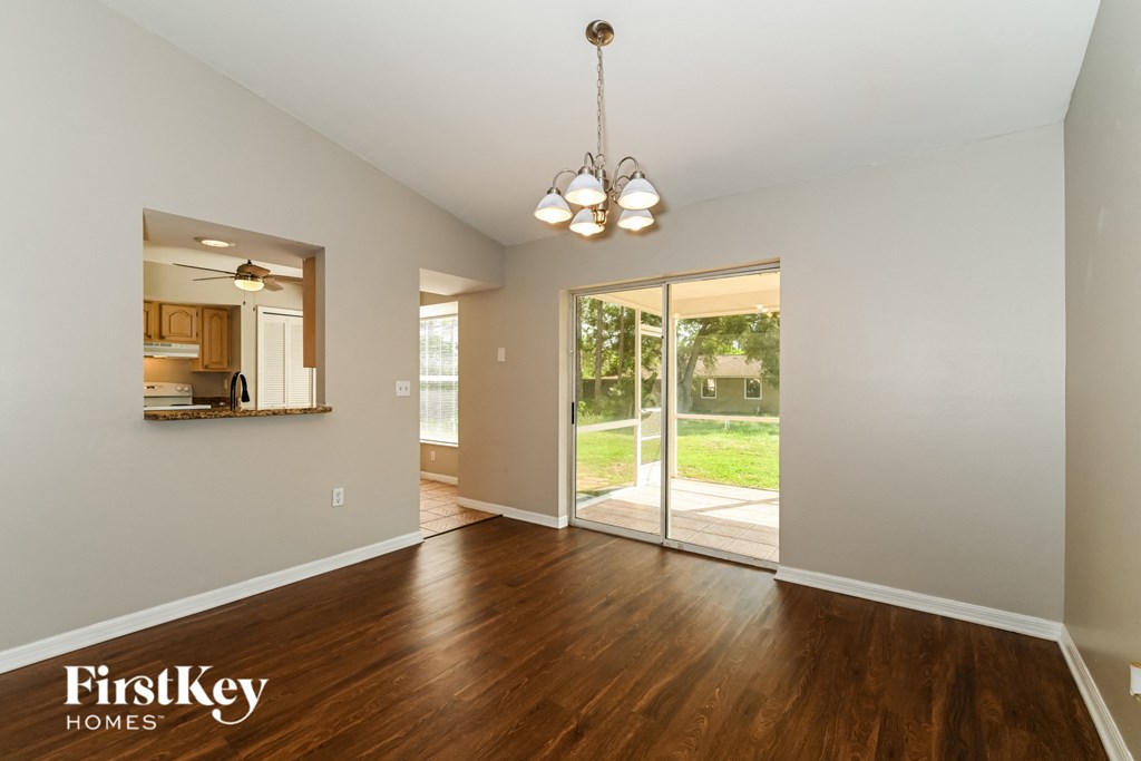 an empty living room with wood flooring and a sliding glass door to a yard