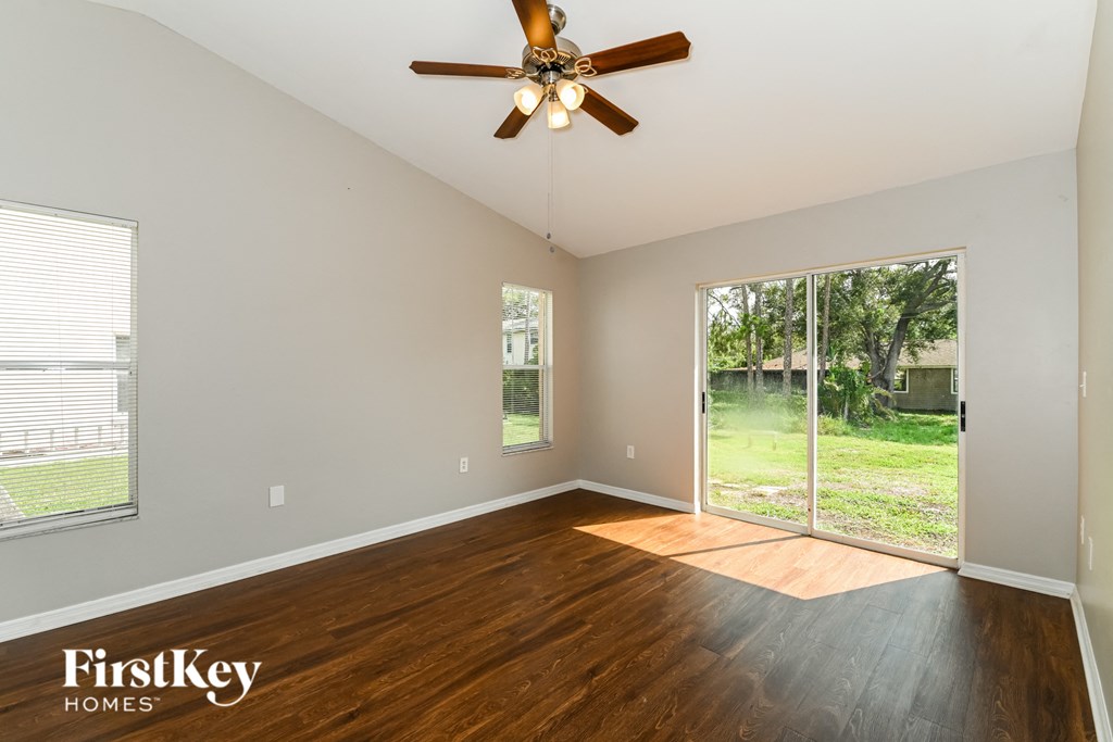 a living room with wood floors and a large window and a ceiling fan