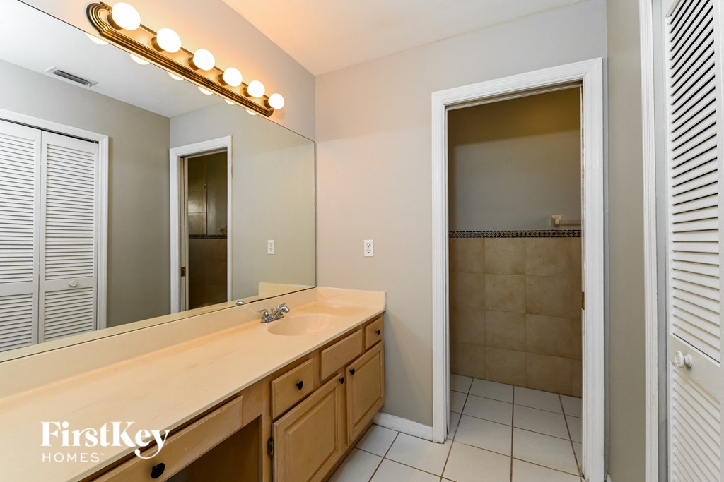 the master bathroom has a large vanity with a large mirror and a shower