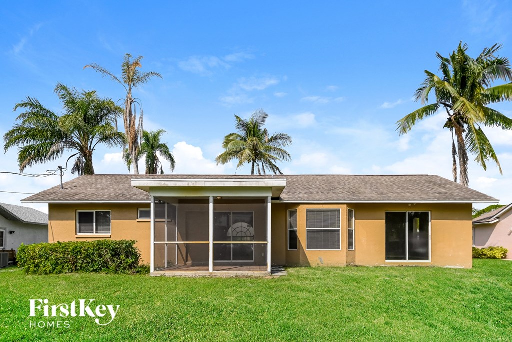 a yellow house with palm trees in the background