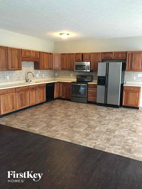 A kitchen with wooden cabinets and a black fridge.