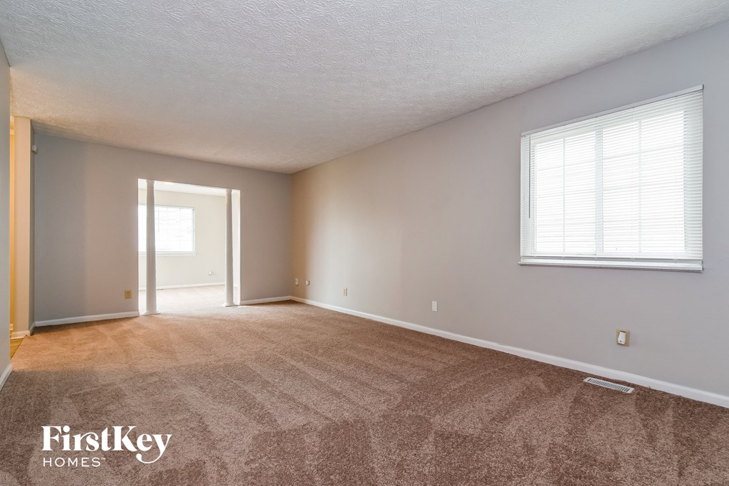the living room of an empty house with carpet and a window