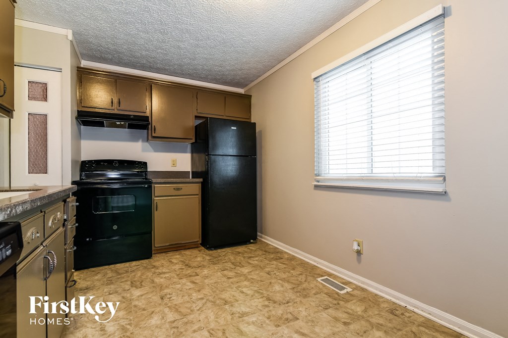 a kitchen with a black stove and refrigerator and a window