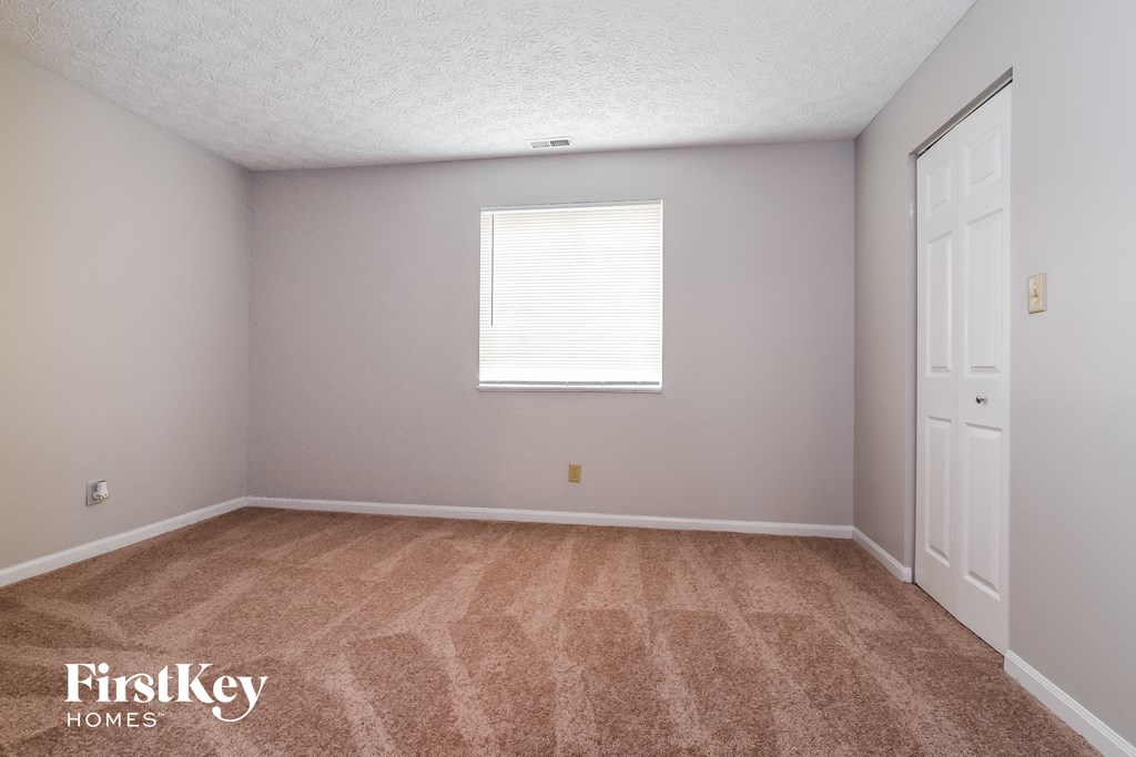 a bedroom with carpet and a window and white doors